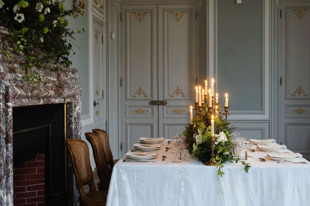 Sala de jantar sofisticada, com mesa iluminada por velas e arranjos florais, em um ambiente de hotel de luxo.
